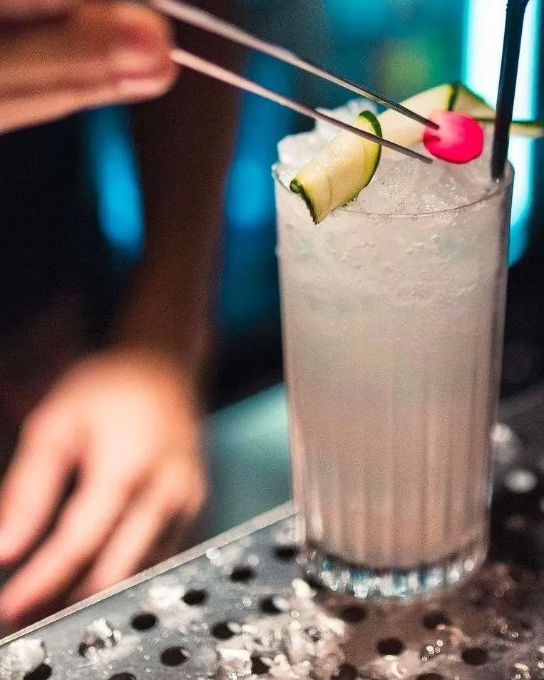 Bartender decorando un cóctel con lima y cereza en la barra de Bloody