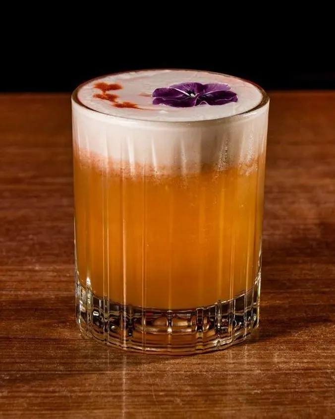 Cóctel Spicy Mango Dream de mango con espuma y flor de violeta